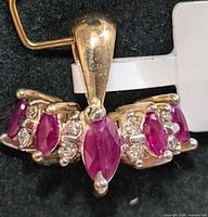 Close-up image of 10KT gold pendant with marquise rubies and small round diamonds from front angle.