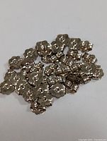 Pile of multiple 10KT gold earring backs against a plain white background, showing their size, shape, and gold metal finish.