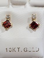 Front view of the pair of earrings displaying square garnet and round diamond stones set in 10KT gold.