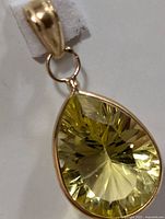Close-up view of 14KT gold pendant with faceted lemon quartz gemstone, showing teardrop shape and gold bail.