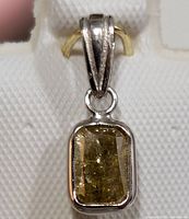 Close-up front view of rectangular fancy yellow diamond pendant bezel-set in 14KT gold with triple bail.