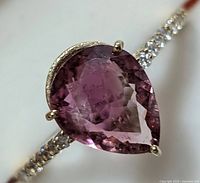 Close-up of pear-shaped tourmaline center stone and diamond-accented band front view