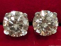 Close-up front view of both diamond stud earrings on red background