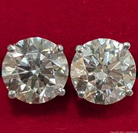 Front view of round brilliant cut lab diamond stud earrings on red background