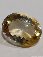 Oval cut genuine citrine gemstone with prominent facets reflecting light in golden yellow tones.
