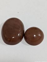 Two polished brown moonstone gemstones placed on white background, showing shape, size, and surface details