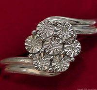 Close-up top view of silver ring showing 7 round-cut diamonds in floral cluster