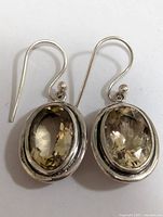 Front view of the pair of silver earrings with oval faceted citrine stones showing the detailed faceting and setting.