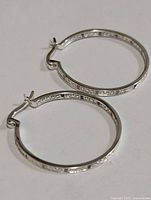 Silver hoop earrings shown from top view, displaying the overall shape and clasp.