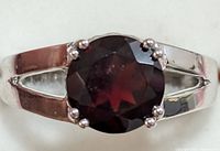 Close-up front view showing the garnet gemstone and silver split shank band.