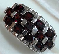 Close-up angled view of the garnet ring showing the multiple oval faceted garnet stones in a two-row setting on sterling silver polished band.