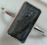 Close-up front view of rectangular labradorite stone set in silver ring band.