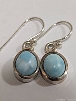 Pair of oval Larimar stone drop earrings set in silver, showing good detail of stone and silver finish.