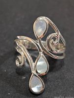 Front view of the silver ring showing the three pear-shaped mother of pearl stones and swirling band design