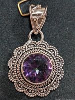 Close-up front view of silver pendant with round purple mystic topaz in decorative beaded and twisted rope silver setting.