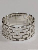 Close-up front view of silver ring showing its interlocking brick design and polished silver finish.