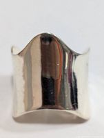 Front view of the silver ring showing smooth, polished reflective surface and wide curved design.