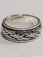 Close-up front view of silver braided ring showing detailed pattern and polished finish.