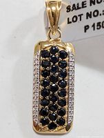 Front and angled views of rectangular silver pendant with multiple round blue sapphire stones and clear accent stones on sides.