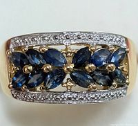 Front view of the gold tone ring showing blue marquise-cut sapphires and clear stone accents