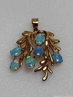 Front view of pendant showing seven oval opal cabochons and gold branch design