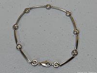 Full view of bracelet laid flat showing alternating bar and round links and lobster clasp