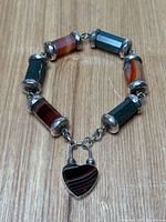 Full view of sterling silver Scottish pebble bracelet laid flat, showing alternating agate and bloodstone barrel beads and heart padlock clasp