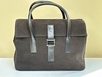 Front view of dark brown suede handbag with smooth leather straps and silver-tone buckle