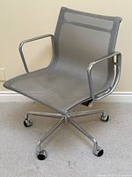 Front three-quarter view of grey mesh seat and polished aluminum frame with casters