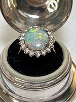 Top-down view of ring on black cushion in metal box