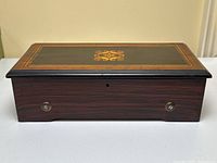Closed rectangular case front view showing rosewood-inlaid lid and faux woodgrain sides