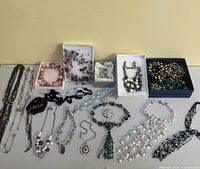 Top-down view of assorted necklaces, earrings, and brooch on table