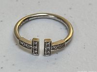 Front view of ring showing diamond-set double T motif