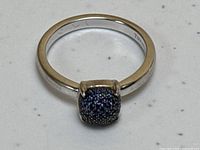 Top-down view of ring on white surface showing cushion-shaped sapphire cluster