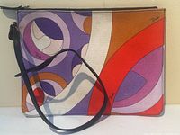 Front view of canvas clutch bag with abstract geometric print, black leather wrist strap attached at zipper.