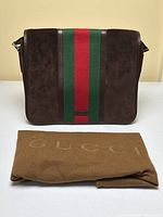 Front view of messenger bag with dust bag laid in front