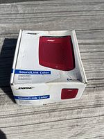 Front view of the Bose SoundLink Color speaker box in white with image of the red speaker.