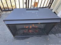 Full view of the electric fireplace showing black metal case with glass front and simulated flames.