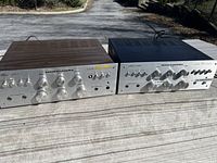 Two amplifiers side by side, front panels visible on outdoor table
