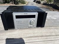 Front view of the Rotel amplifier with silver faceplate, buttons, and dial in outdoor lighting.