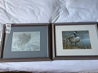 Two Robert Bateman framed prints displayed side by side on a white fabric background.