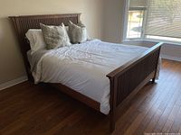 Front view of assembled bed showing headboard, footboard, mattress with protective cover and box spring