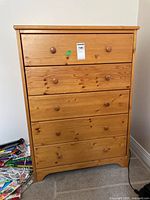 Front view of pine wood dresser showing five drawers and round wooden knobs.
