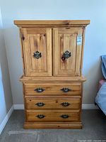 Front view of the wood dresser showing two cabinet doors and three drawers with metal handles, visible wood grain and scratches.