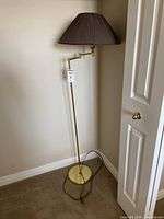 Full view of the brass-tone floor lamp with brown pleated shade in corner