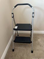 Front view of Gorilla two-step folding step stool, showing black cushioned handle and steps