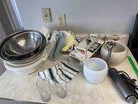 Overview photo of kitchen items including bowls, colander, glass cups, towels, and kitchen tools.