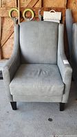 Front view of a grey leather easy chair showing wide seat, high back, and armrests with wear marks.