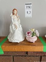 Photo showing the Royal Doulton Barbara figurine alongside the Royal China floral arrangement on a wooden surface with a label showing measurements.
