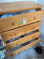Wooden dresser with four drawers, partially open showing linens inside.